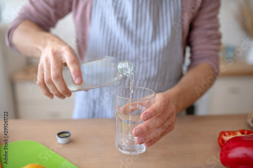 Top view of man pouring still water into glass
