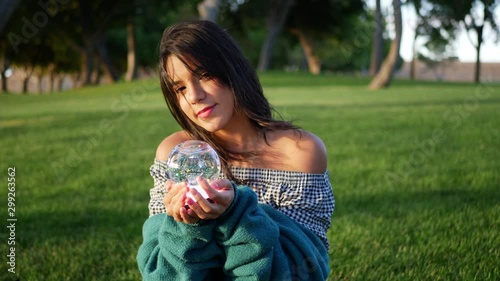 A cute young hispanic woman smiling happily in a park with a magic crystal ball. photo