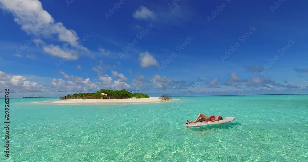 woman sunbathing on a surfboard in the ocean woman sunbathing on a surfboard in the ocean