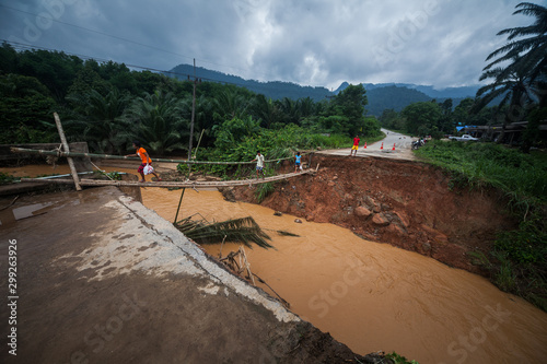 KRABI / THAILAND - APRIL 01, 2011: Local people cross the rapid dirty river on the bamboo bridge after their old solid bridge was washed away and asphalt road was damaged during tropical flood