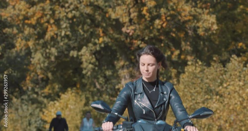 Wallpaper Mural Front view of beautiful woman hair waving in wind, Female Biker wearing leather jacket On road with autumn leaf color Trees at amelisweerd forest on sunny day. Slow Motion in Utrecht, Netherlands Torontodigital.ca