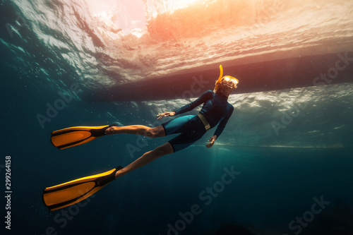 Woman freediver swims underwater under the boat