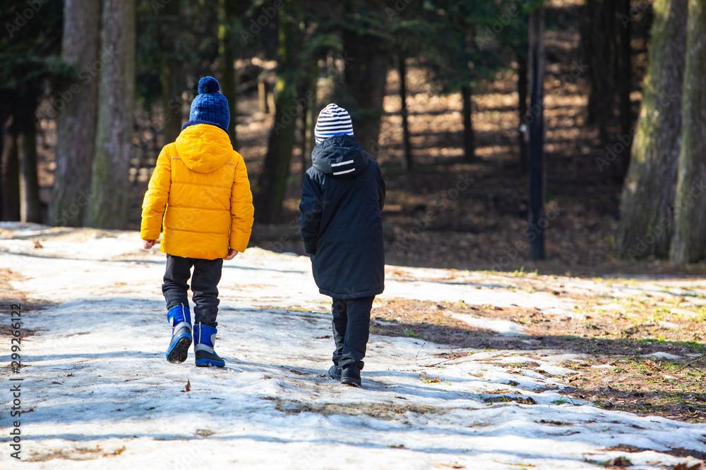 two boys in winter clothes walking by snowed park two boys in winter clothes walking by snowed park