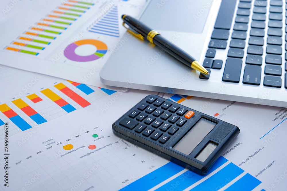 Laptop and pen with business charts, graphs, statistic and documents background for business and finance concepts Laptop and pen with business charts, graphs, statistic and documents background for business and finance concepts