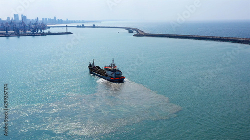 Suction Dredger ship working near the port with mud, Pollution, brown Muddy water - aerial shot