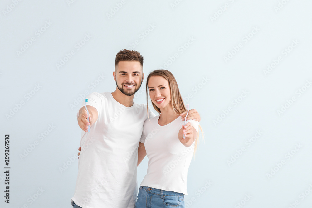 Portrait of young couple with toothbrushes on light background - obrazy, fototapety, plakaty 