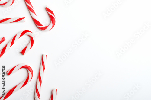 Blank frame with Christmas candy canes top view. New Year lollipops on white background. Winter holidays backdrop with copyspace. Xmas confection composition with decorative elements. © mellisandra