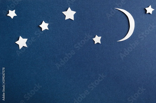 Moon and stars on blue background top view. Night sky objects with shadow close up. Decorative backdrop. Childish applique, homemade postcard. Starry heaven. Kid bedtime, nighttime concept.