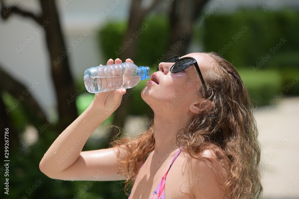 Beautiful girl in a bathing suit is drinking water from a bottle Beautiful girl in a bathing suit is drinking water from a bottle
