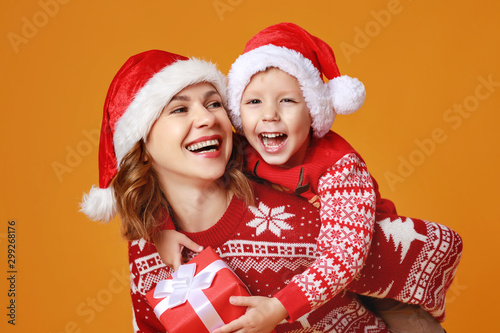 happy family mother and child son with christmas gifts on yellow background