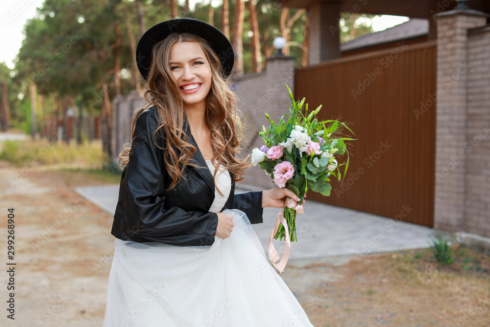 Fototapeta premium Beautiful young bride with bouquet of flowers on her wedding day outdoors