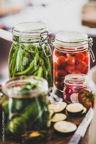 Autumn vegetable pickling and canning. Ingredients for cooking and glass jars with homemade vegetables preserves on wooden table, close-up. Healthy organic fermented food concept photo