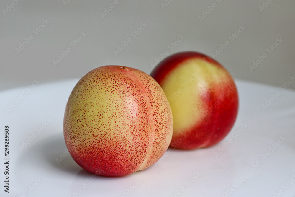 Two delicious ripe juicy nectarines on a white plate. Healthy fruits, vitamins. Two delicious ripe juicy nectarines on a white plate. Healthy fruits, vitamins.