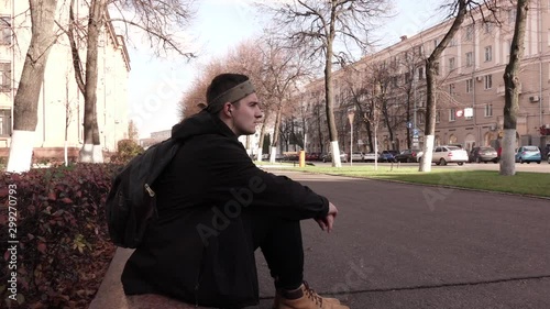 Timelapse of a young man sitting still on the sidewalk in a crowd of people moving fast.