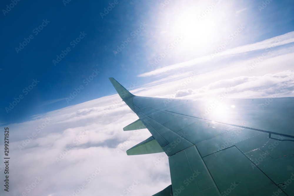 Fototapeta premium Wing of an airplane flying above the clouds