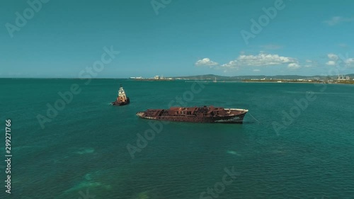 Drone footage of 2 abandoned boats at different angles surrounded by beautiful teal water and clear blue skies photo