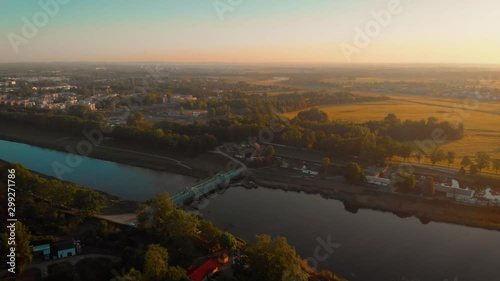 an aerial shot of a river in Poland at sunrise with a green bridge and green yellow in the background photo