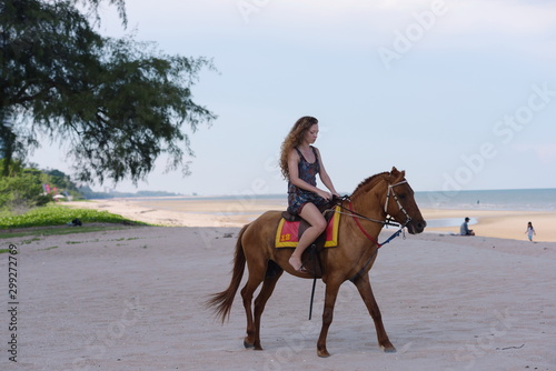 A beautiful girl riding a horse and playing happily at the beach