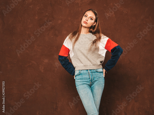 Young beautiful woman looking at camera. Trendy girl in casual summer shirt clothes with natural makeup. Positive female. Funny model posing near blue wall in studio