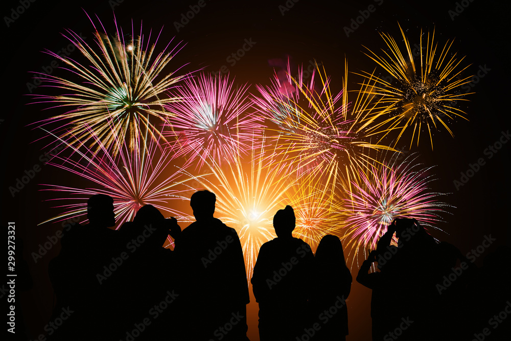 Crowd watching fireworks and celebration. Happy family sitting on floor and watching the fireworks Celebration at night on New Year and copy space - abstract holiday background.