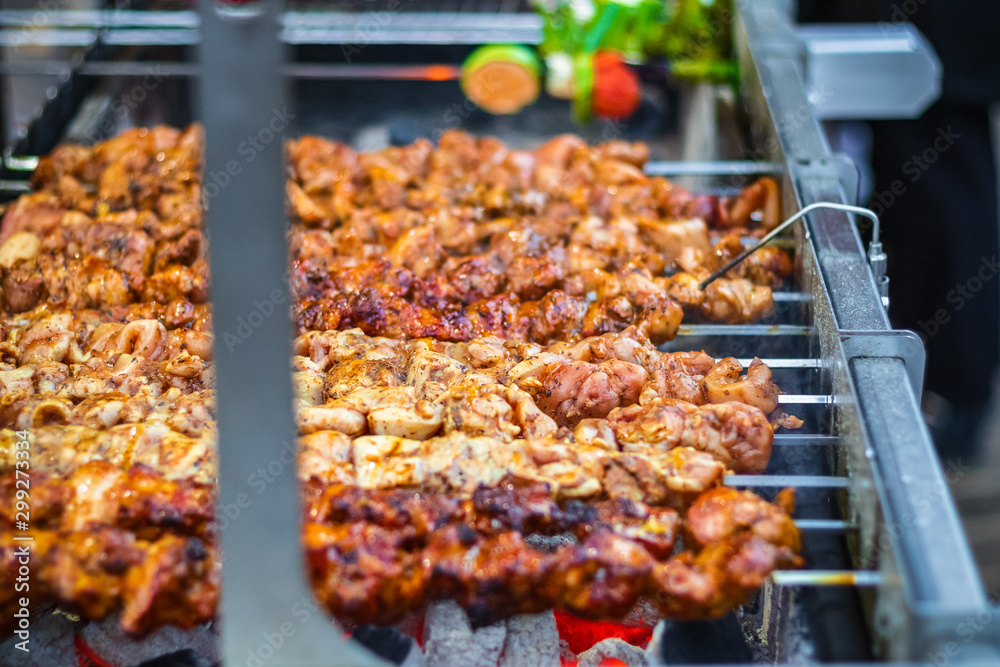 Selective focus, chicken kebabs cooking on a charcoal grill at Christmas market winter wonderland in London Selective focus, chicken kebabs cooking on a charcoal grill at Christmas market winter wonderland in London