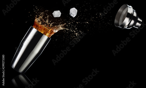 ice cubes and cocktail spilling out of a shaker isolated on black background photo