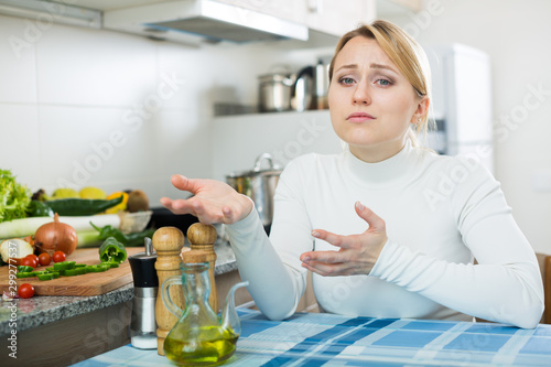 Miserable young woman in domestic kitchen