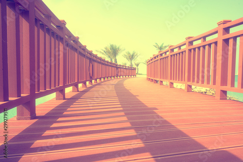 Walkway red wooden bridge with morning sunlight and shadow over foggy sky background © Jantira