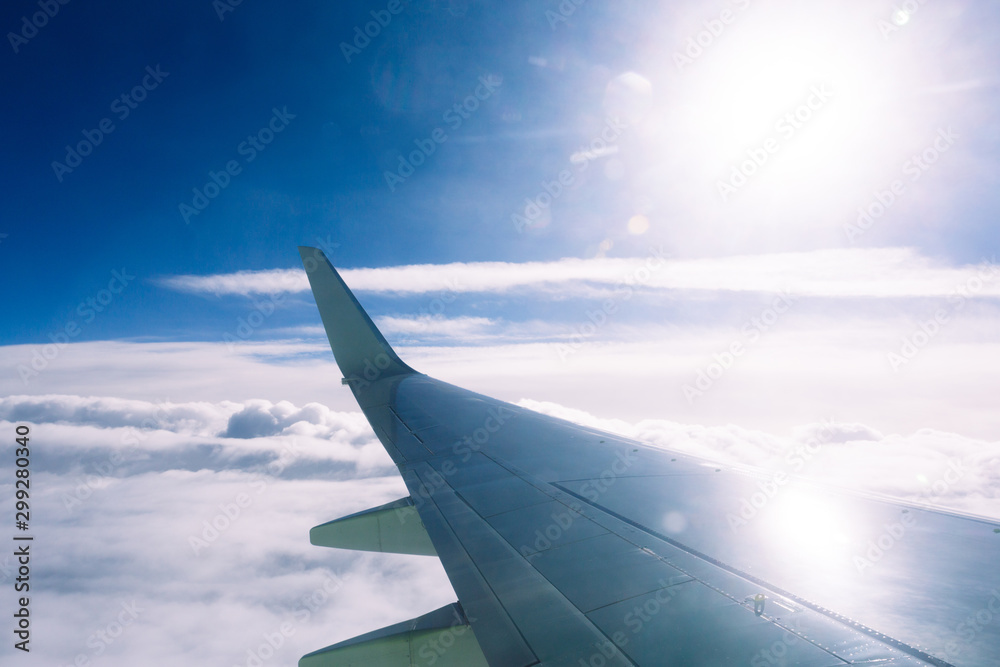 Fototapeta premium Wing of an airplane flying above the clouds