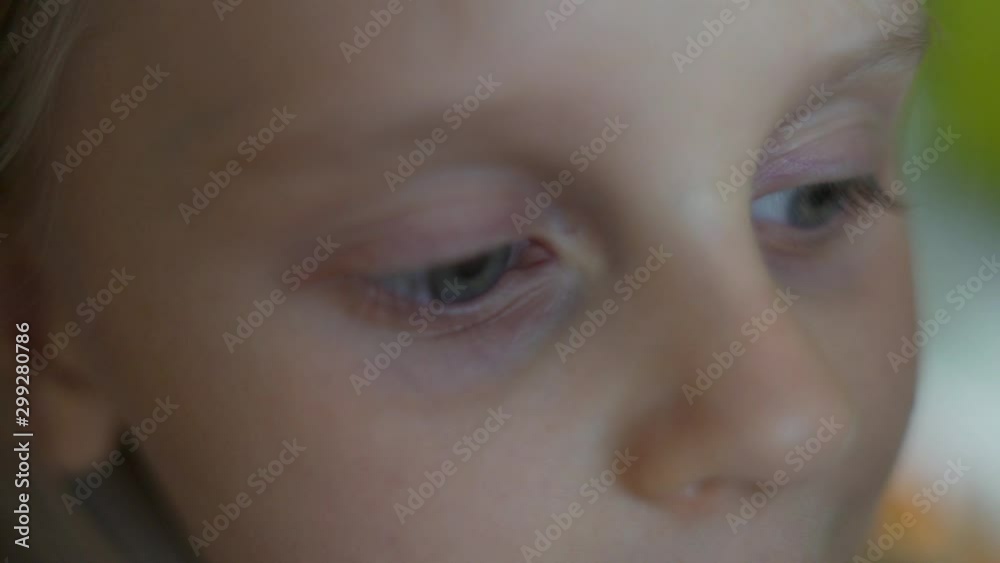 Close-up macro of gray-blue eyes and nose of a cheerful and happy little child, a small blond light-skinned girl