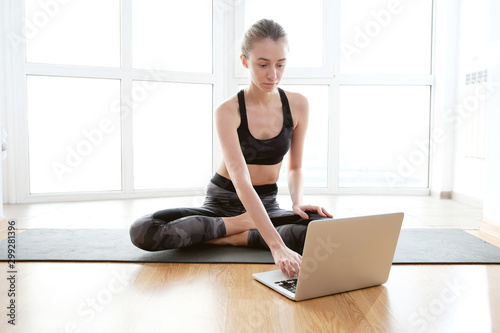 Woman using laptop while sitting on yoga mat