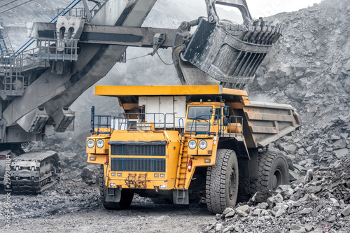 Powerful and large excavator bucket. Loading of minerals into the body of a mining truck.