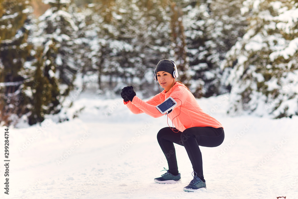 Athletic girl does squats for legs in nature in winter