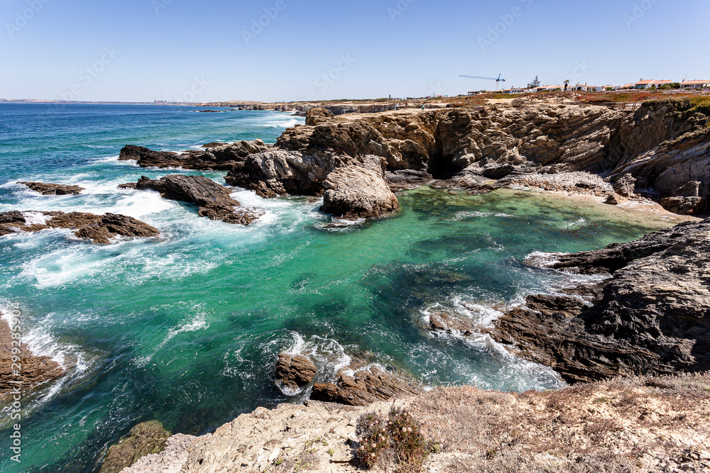 Enseada de águas transparentes protegida das ondas do mar pelos rochedos no Alentejo em Portugal.