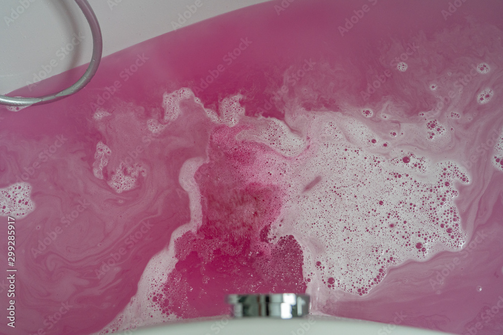 Bathtub with pink bath water and white foam