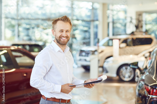 Foto A car dealer smiling standing in a showroom.