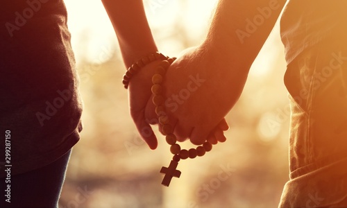 Family praying, closeup man and woman holding hands and prayer rope photo