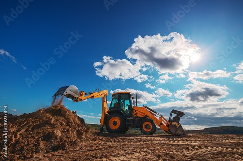 Wheel loader excavator with field background during earthmoving work, construction building
