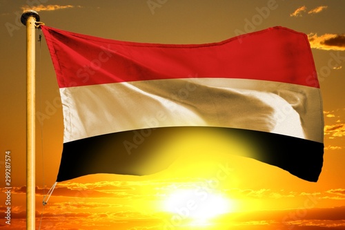 Yemen flag weaving on the beautiful orange sunset with clouds background