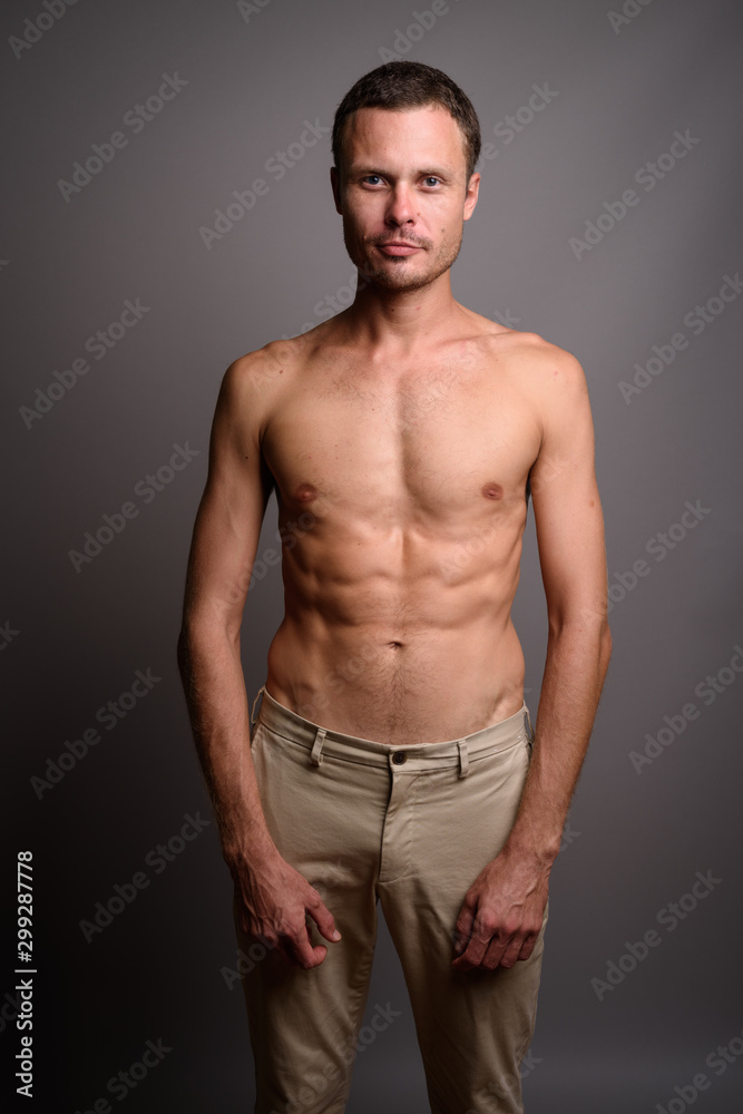 Portrait of handsome man shirtless against gray background Portrait of handsome man shirtless against gray background