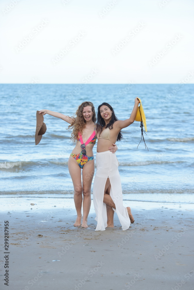 Two beautiful girls in Swimwear for a walk on the beach happily Two beautiful girls in Swimwear for a walk on the beach happily