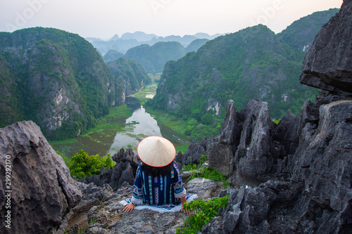 happy woman sitting on peak of mountain at Mua Cave, Ninh Binh, Vietnam at evening, subject is blurred, low key and noise. photo