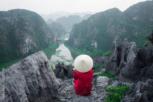 happy woman sitting on peak of mountain at Mua Cave, Ninh Binh, Vietnam at evening, subject is blurred, low key and noise. photo