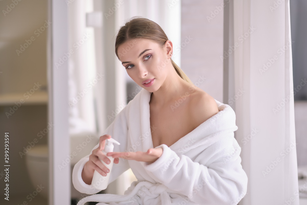 Young woman with flawless skin, applying moisturizing cream on her face.  Photo of woman after bath in white bathrobe and towel on white background.  Skin care concept Stock Photo | Adobe Stock
