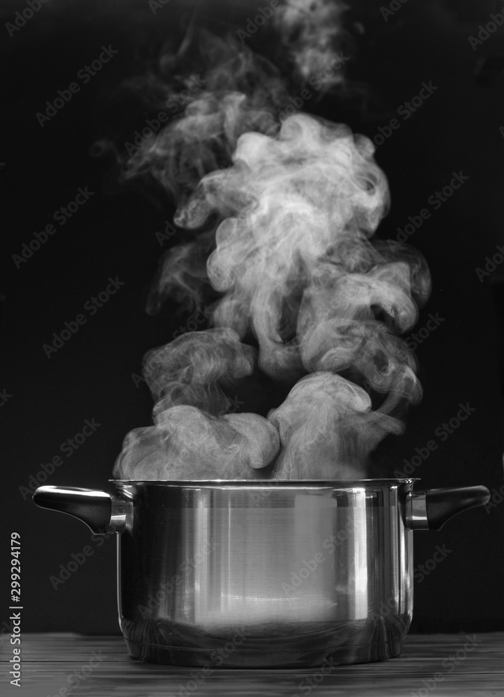 Steaming pot on black background. Smoke above boiling soup pot. Stock Photo  | Adobe Stock