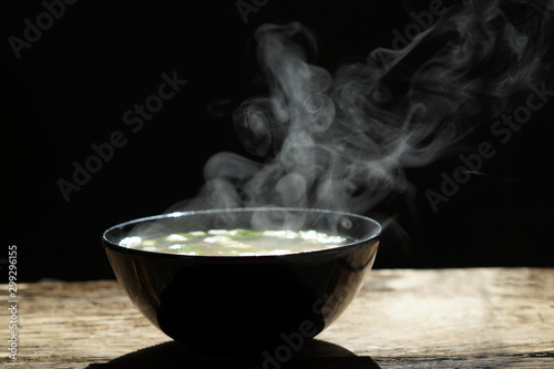bowl of hot soup with steaming on wooden table on black background. Hot food consept.