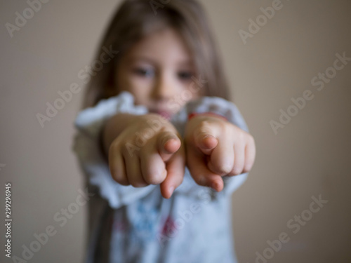 portrait of unhappy little girl the blonde points his index fingers at the camera, the concept of child protection