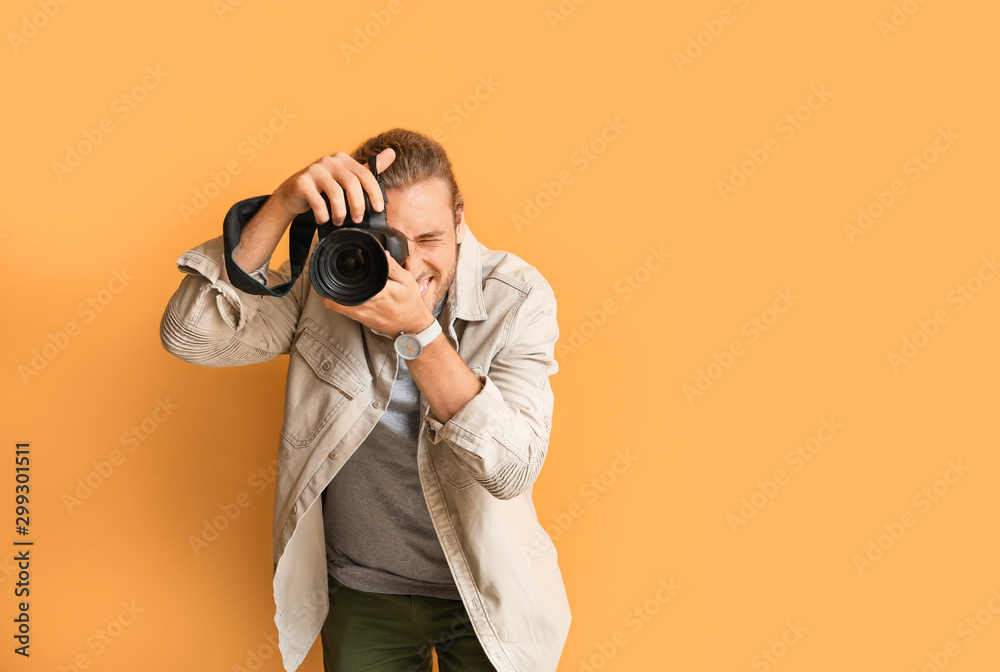 Young male photographer on color background - obrazy, fototapety, plakaty 