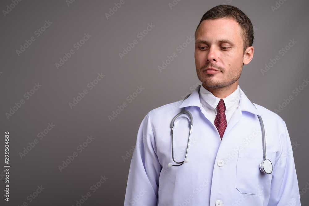 Portrait of handsome man doctor against gray background Portrait of handsome man doctor against gray background