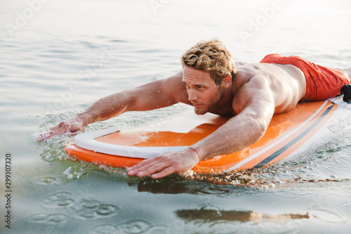 Handsome young man surfer with surfing desk at the beach © Drobot Dean